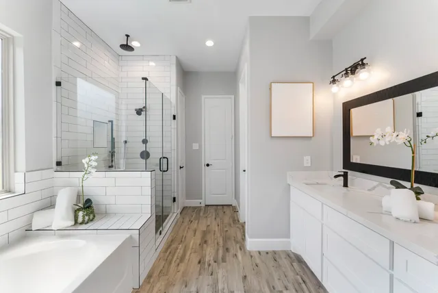 a bathroom with a double vanity sink a mirror a bathtub and shower