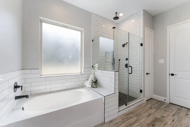 a bathroom with a tub shower sink and mirror