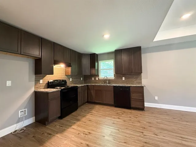 a large kitchen with granite countertop a stove and a sink
