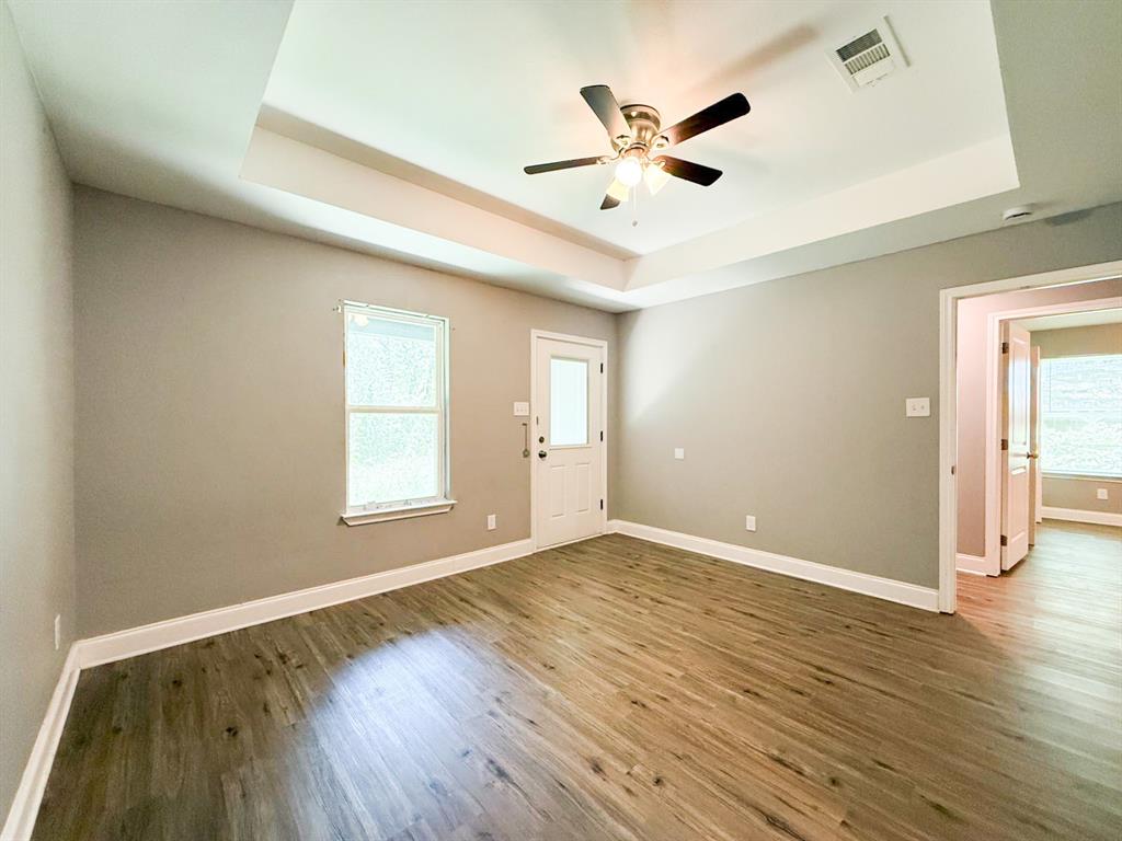 902 Cedar Street Commerce, TX 75428 - Photo 7 of 11 an empty room with wooden floor and windows