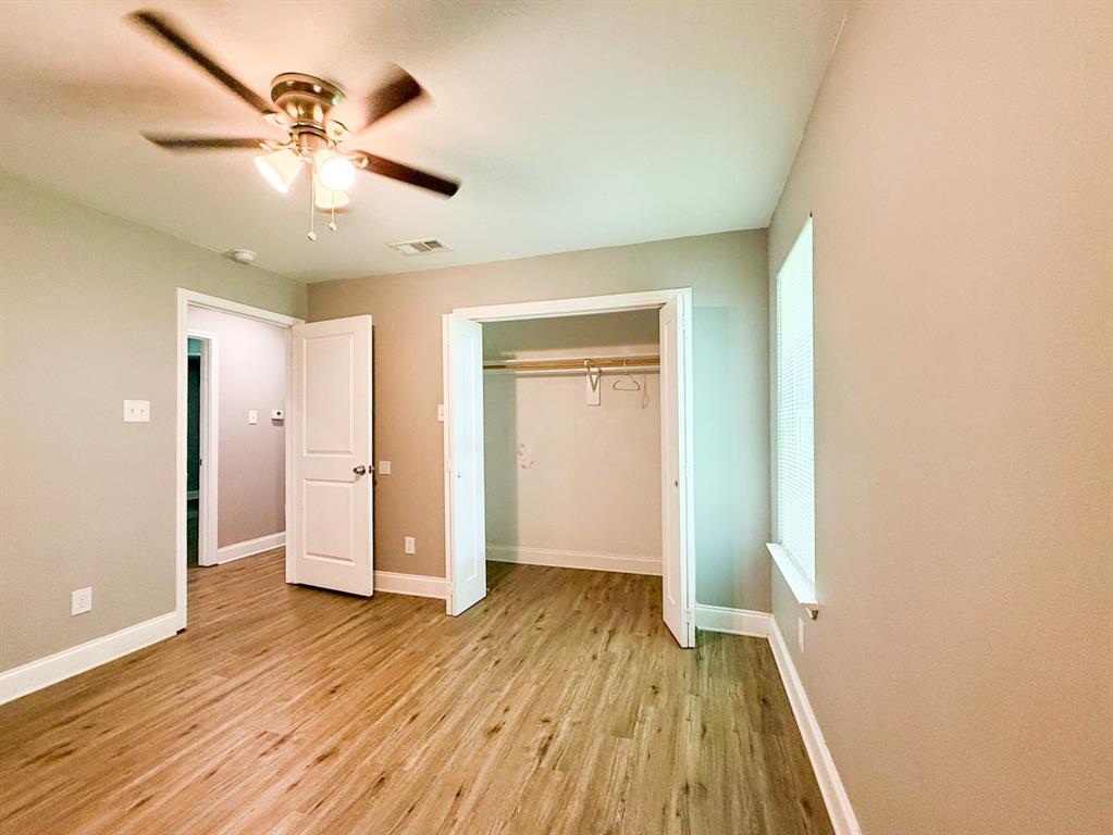 902 Cedar Street Commerce, TX 75428 - Photo 9 of 11 wooden floor in an empty room with a window