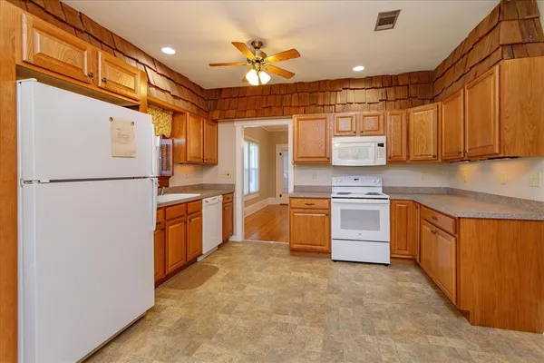 a kitchen with stainless steel appliances granite countertop a refrigerator a sink and white cabinets
