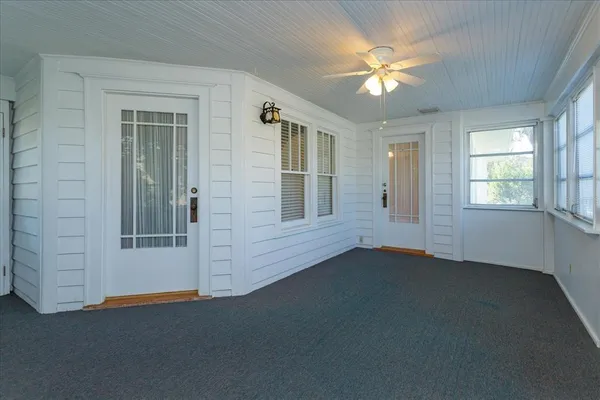 an empty room with windows and ceiling fan