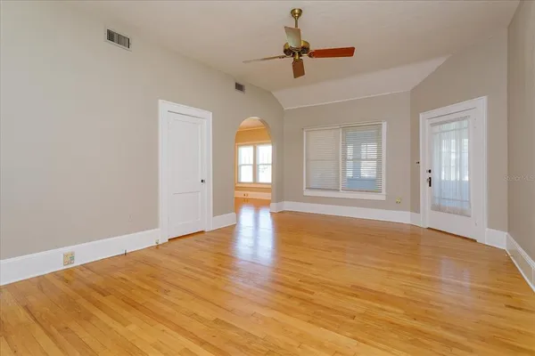 a view of empty room with wooden floor and fan