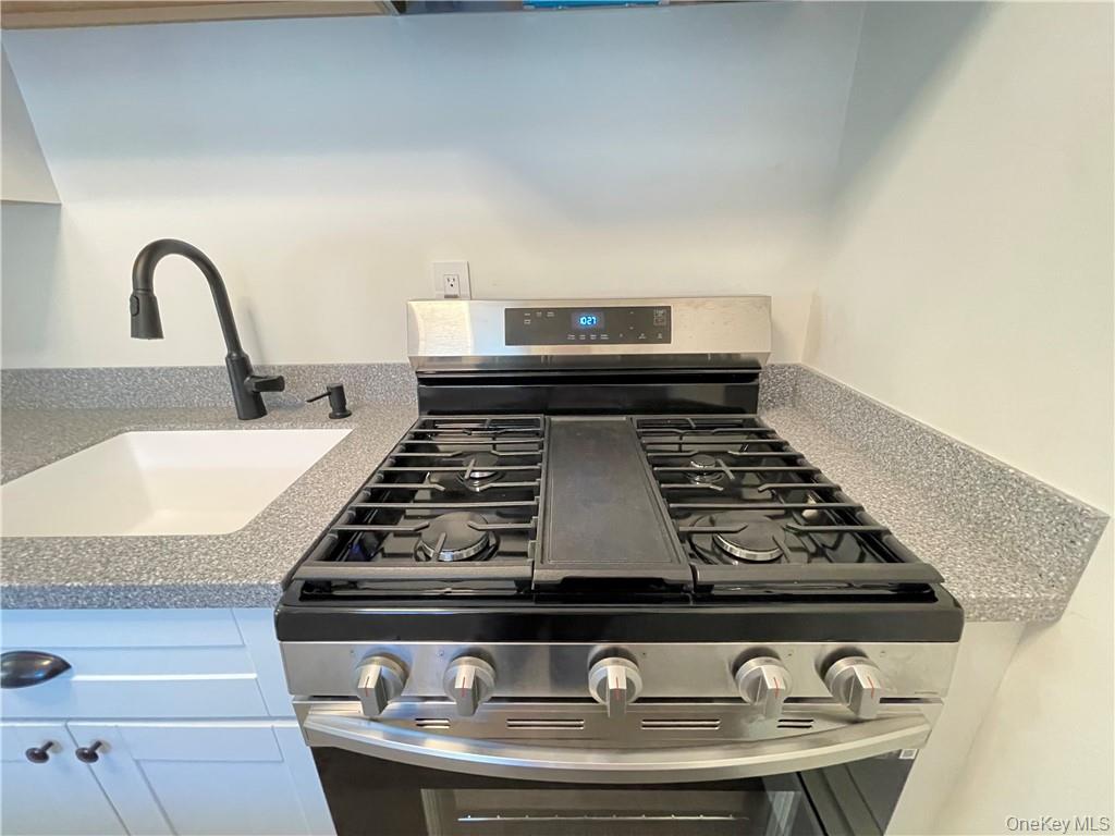 27 Tanager Road, Unit 2702 Monroe, NY 10950 - Photo 7 of 17 Modern kitchen featuring a stainless steel range with griddle, speckled countertops, a large single-basin sink, and a matte black gooseneck faucet