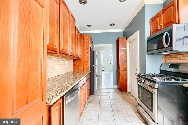 a kitchen with stainless steel appliances granite countertop a stove top oven a sink and a refrigerator