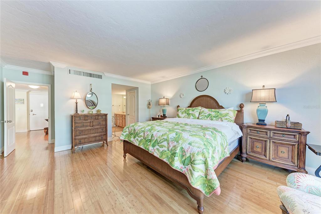 1212 Benjamin Franklin Drive, Unit 208 Sarasota, FL 34236 - Photo 13 of 32 a spacious bedroom with a bed and wooden floor