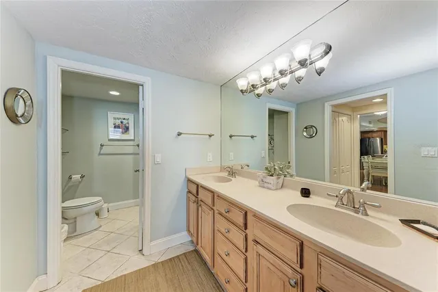 a spacious bathroom with a double vanity sink a toilet and a mirror