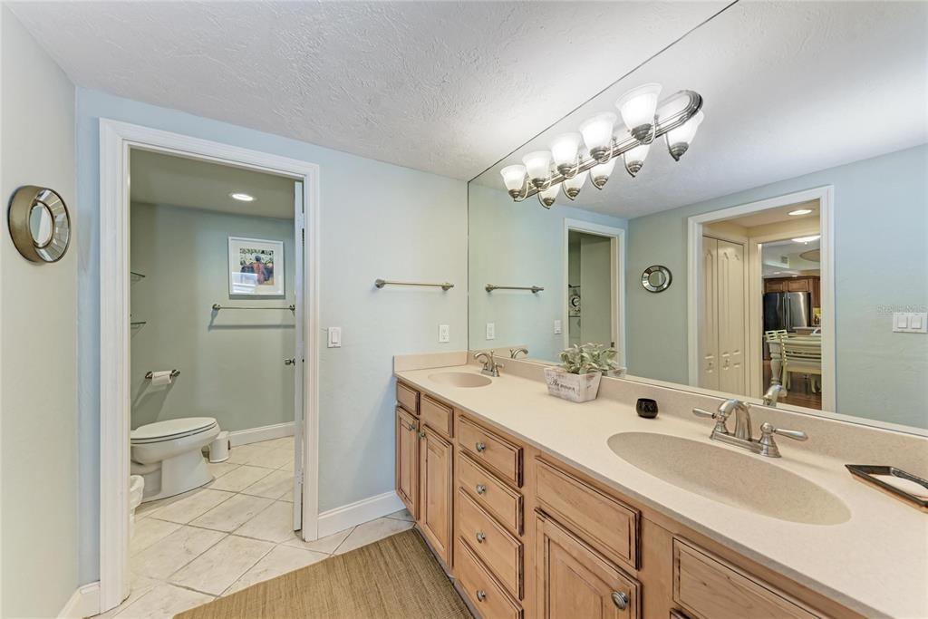 1212 Benjamin Franklin Drive, Unit 208 Sarasota, FL 34236 - Photo 14 of 32 a spacious bathroom with a double vanity sink a toilet and a mirror