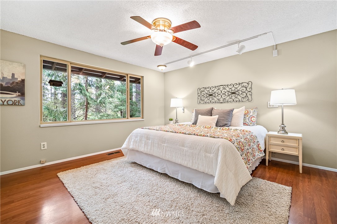 15713 Southeast 148th Street Renton, WA 98059 - Photo 17 of 39 a bedroom with a large bed chandelier and a large window