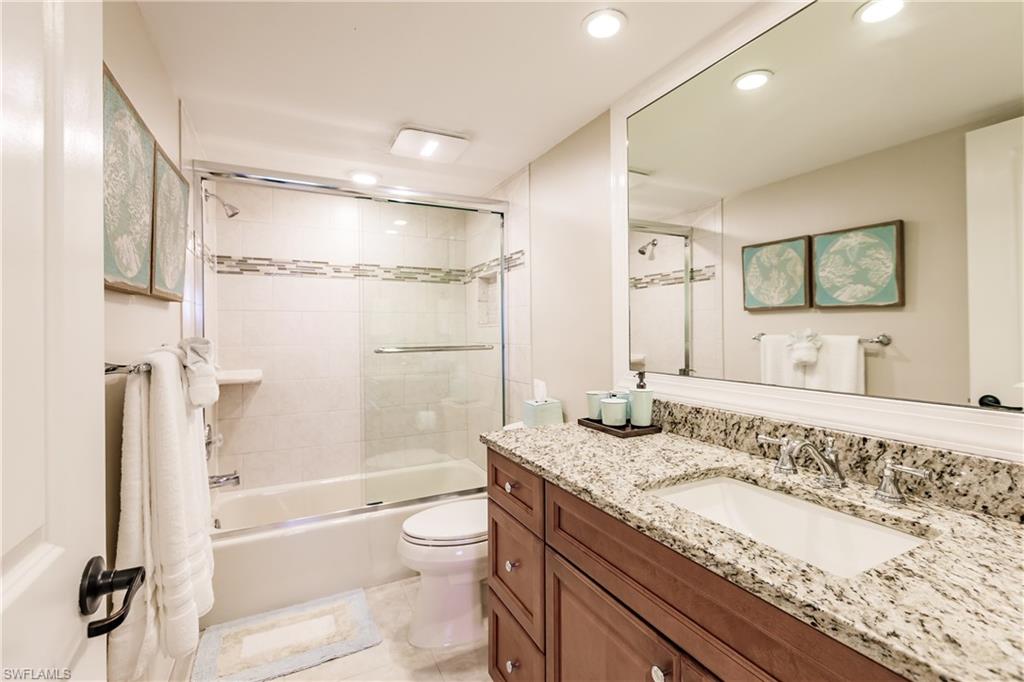 17 Bluebill Avenue, Unit 1005R Naples, FL 34108 - Photo 10 of 33 a bathroom with a granite countertop sink a mirror a bathtub and shower