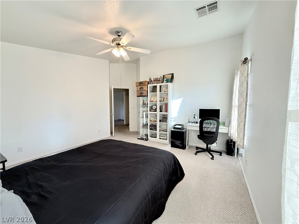 1220 East Gamebird Road Pahrump, NV 89048 - Photo 14 of 49 A well-lit bedroom features vaulted ceilings and light-colored carpeting, creating an airy atmosphere.