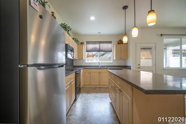 a kitchen with stainless steel appliances granite countertop a refrigerator a sink a stove and a wooden floors