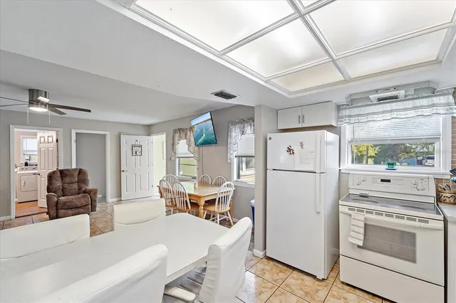 a kitchen with a refrigerator a stove and a dining table with wooden floors