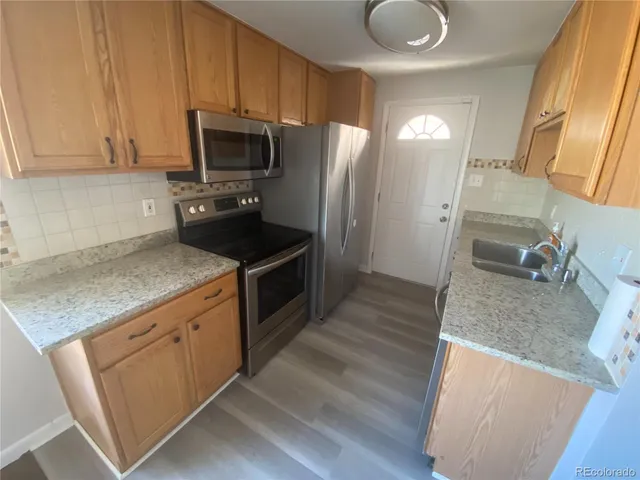 a kitchen with granite countertop a sink a stove and refrigerator