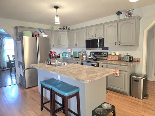 a kitchen with stainless steel appliances granite countertop a refrigerator a stove top oven a sink dishwasher and white cabinets with wooden floor