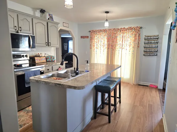 a kitchen with a stove a sink dishwasher a refrigerator and a dining table with wooden floor