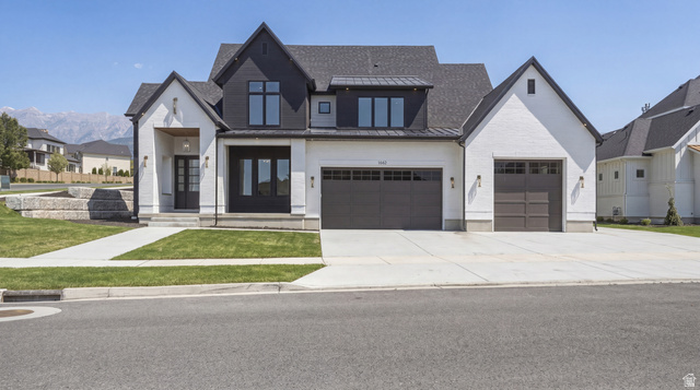 1682 North 1950 W Street, Unit 9 Provo, UT 84604 - Photo 3 of 84 Modern farmhouse exterior featuring a black and white facade, a two-car garage, an additional single-car garage, a covered entryway, and mountain scenery
