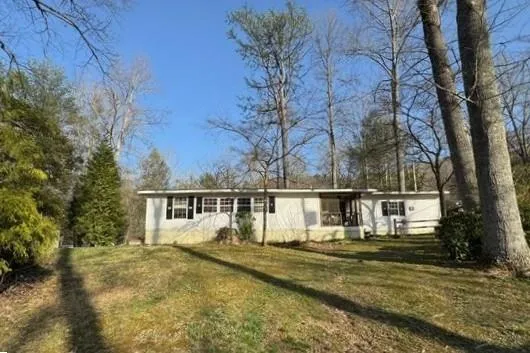 a view of a house with large trees and a yard