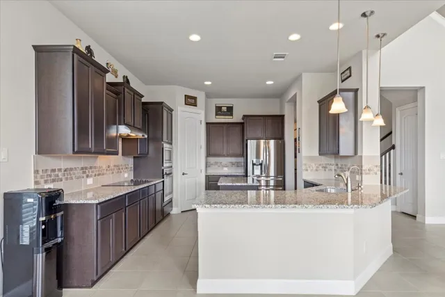 a large kitchen with kitchen island a sink stainless steel appliances and cabinets