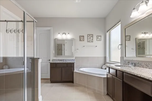 a bathroom with a granite countertop bathtub sink vanity and mirror