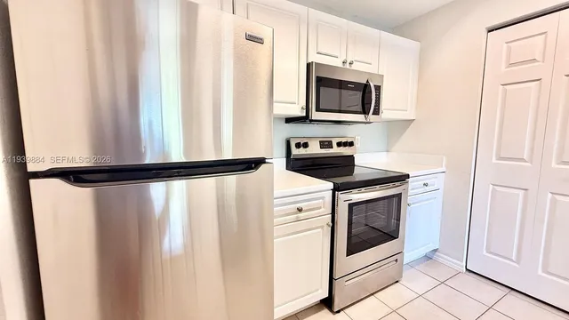 a kitchen with white cabinets and black appliances