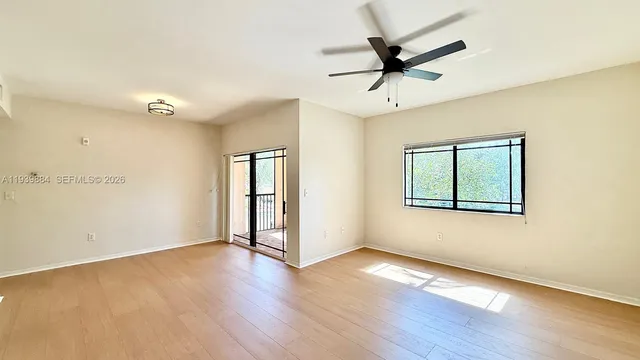 an empty room with wooden floor fan and windows