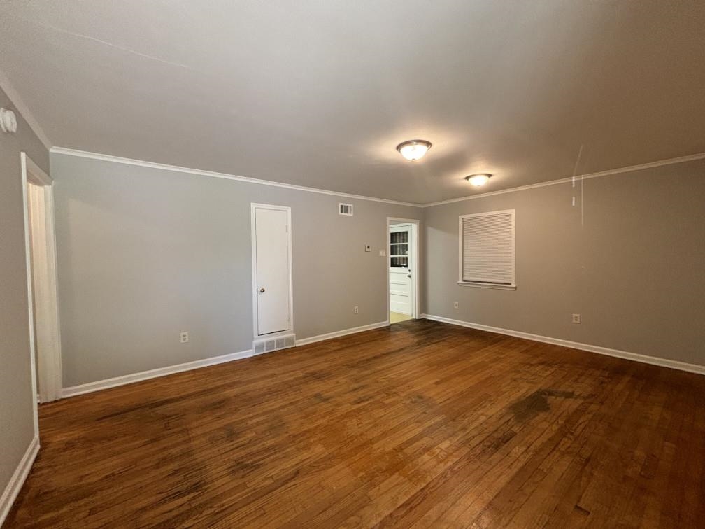3011 Christine Road Memphis, TN 38118 - Photo 4 of 26 Spare room with dark wood-style floors, visible vents, baseboards, attic access, and crown molding