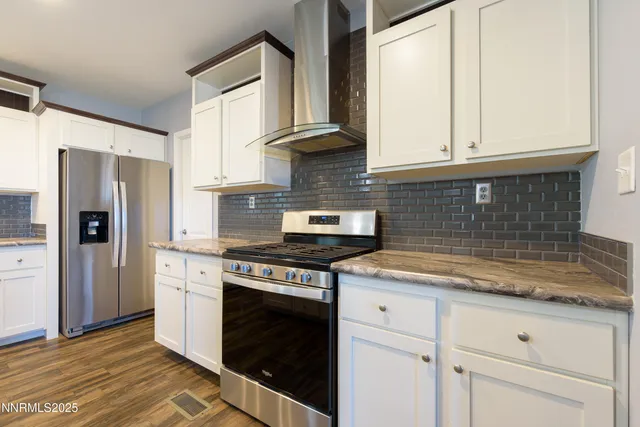 a kitchen with stainless steel appliances kitchen island granite countertop a stove refrigerator and cabinets