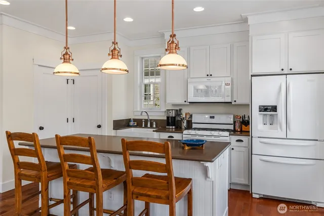 a kitchen with stainless steel appliances a refrigerator a stove a sink dishwasher and white cabinets with wooden floor