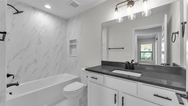 a bathroom with a granite countertop sink a toilet a bathtub and shower