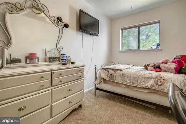 a bedroom with a bed and a flat tv screen on the dresser
