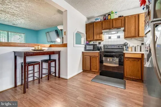 a kitchen with stainless steel appliances granite countertop a stove top oven a sink dishwasher and a refrigerator