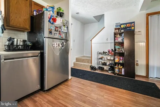 a view of a kitchen with fridge and wooden floor
