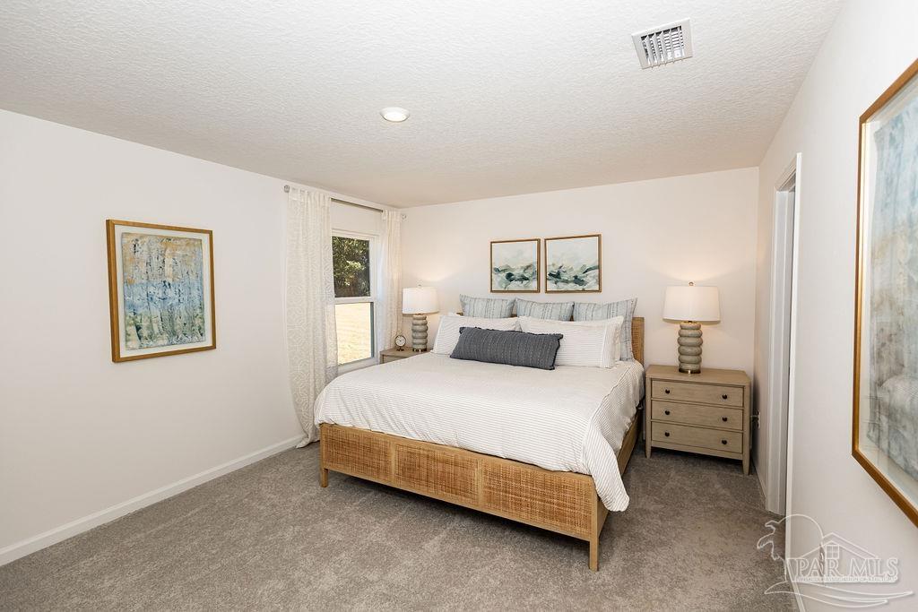 7761 Moonrise Way Milton, FL 32583 - Photo 8 of 19 a spacious bedroom with a bed and a lamp