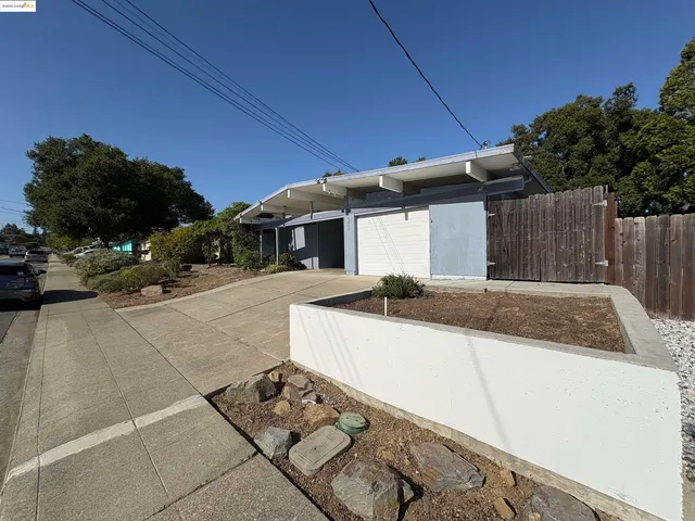 a view of a backyard with couches under an umbrella