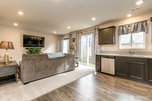 a large living room with stainless steel appliances granite countertop a stove a sink dishwasher a microwave oven and a refrigerator with wooden floor