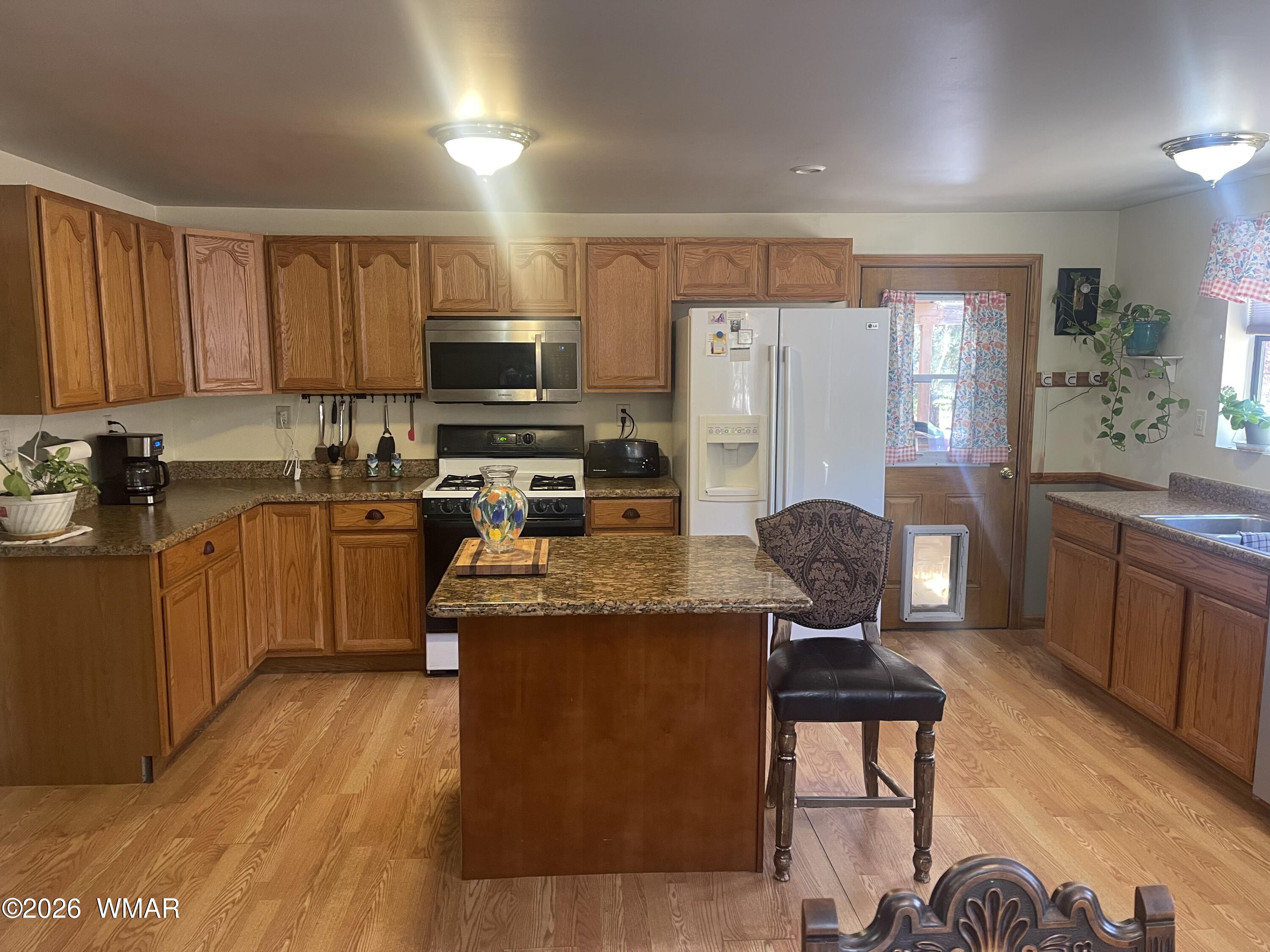 2871 Moose Trail Overgaard, AZ 85933 - Photo 8 of 25 a kitchen with stainless steel appliances granite countertop a stove top oven a sink dishwasher a dining table and chairs with wooden floor