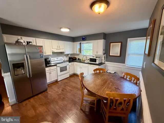 a kitchen with stainless steel appliances granite countertop a stove a refrigerator a sink a dining table and chairs