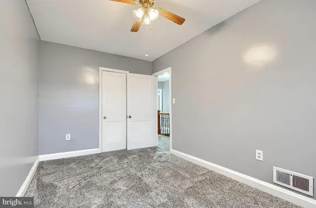 an empty room with a chandelier fan and windows