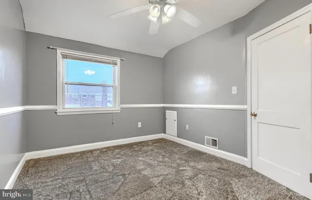 an empty room with a fan & windows