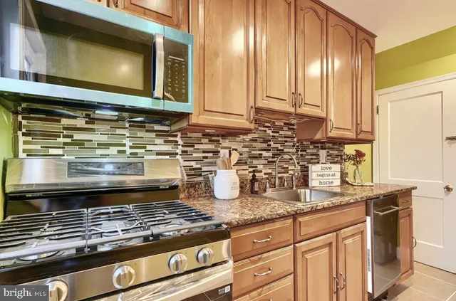 a kitchen with granite countertop a stove a sink and a microwave