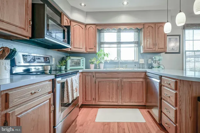 a kitchen with granite countertop a stove a sink and dishwasher wooden cabinets with a large window