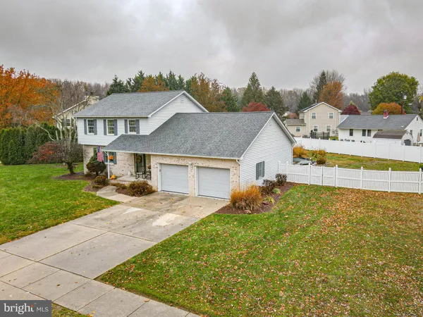 a front view of house with yard and trees in the background