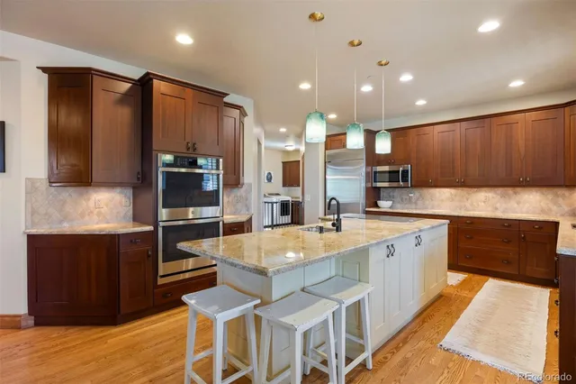 a large kitchen with kitchen island granite countertop wooden cabinets and stainless steel appliances