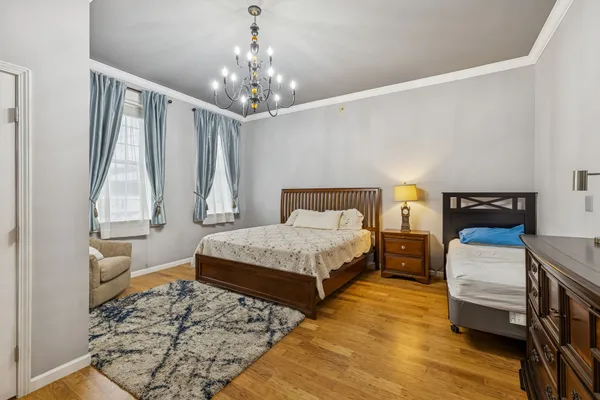 a bedroom with a bed wooden floor and a chandelier