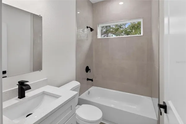 a bathroom with a granite countertop bathtub sink vanity mirror and toilet