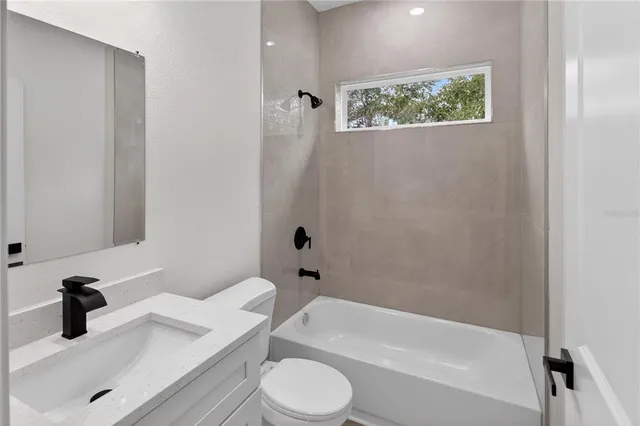 a bathroom with a granite countertop bathtub sink vanity mirror and toilet
