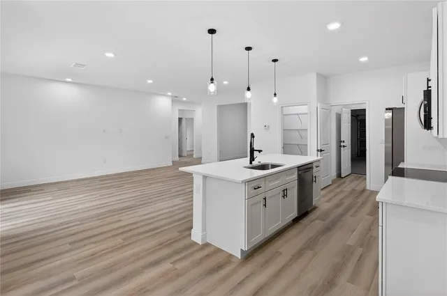 a large kitchen with granite countertop a large counter top a sink stainless steel appliances and cabinets