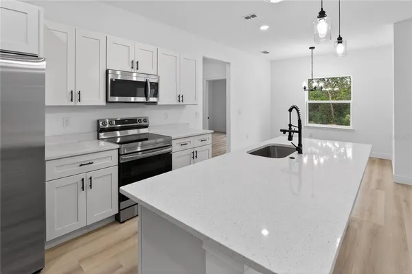a kitchen with stainless steel appliances a white table chairs and a refrigerator